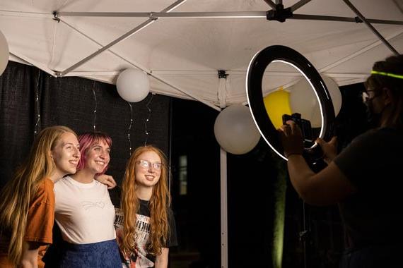 三个学生在环形灯前摆姿势拍照，背景是气球
